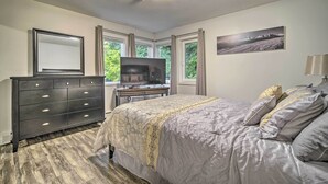 A bedroom with a bed, dresser, TV, windows, and a painting. - Walk to Downtown & Coast Trail: Condo in Anchorage (Anchorage)