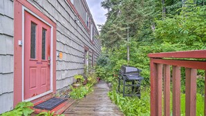 A narrow wooden pathway leading to a red door, surrounded by lush greenery and a wooden fence. - Walk to Downtown & Coast Trail: Condo in Anchorage (Anchorage)