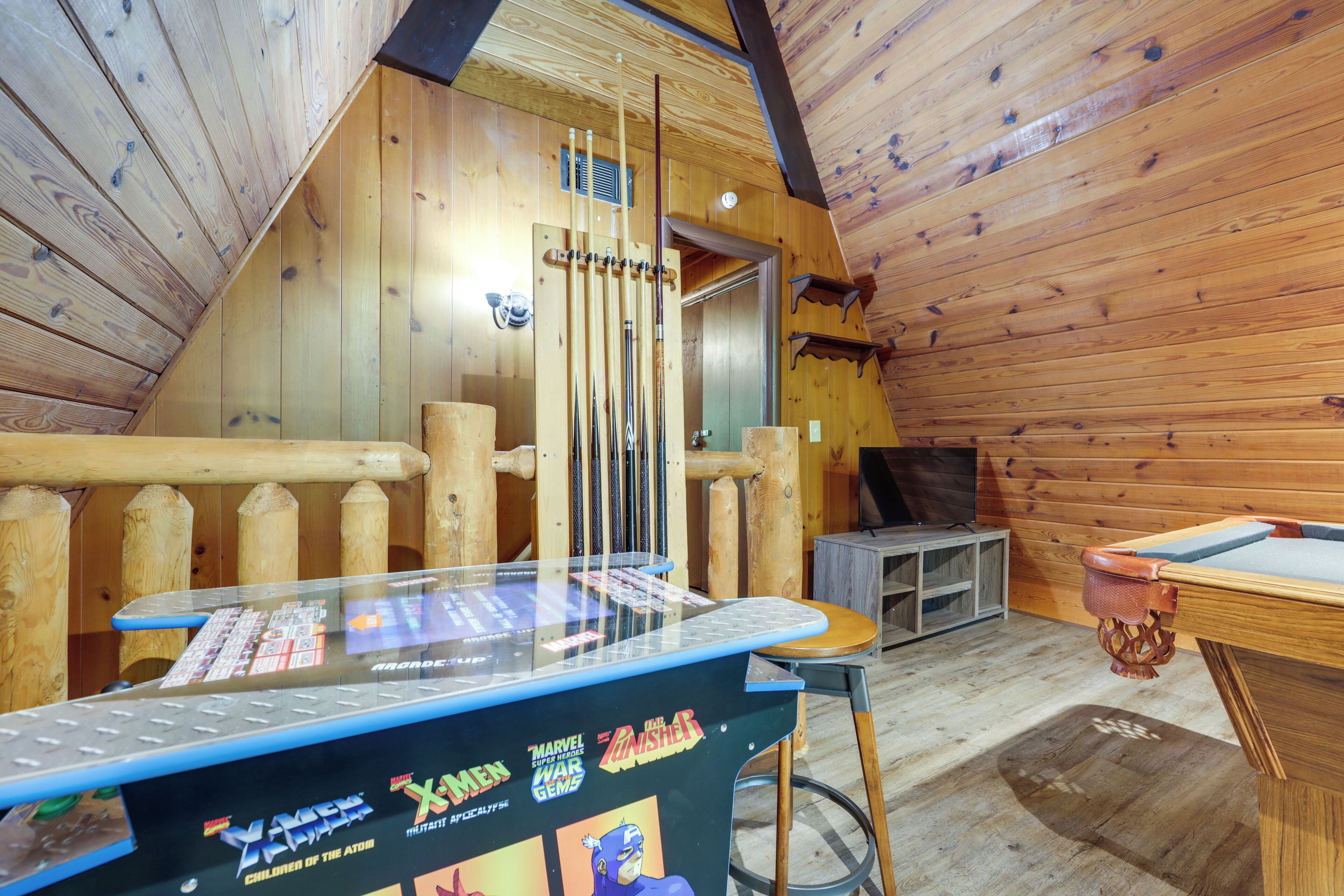 Un intérieur en bois comprenant une table de billard, un porte-taquets et un petit coin salon.