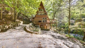 A cabin with a sloped roof, surrounded by trees and a paved path leading to it. - Cabin w/ Hot Tub: 2 Mi to Downtown Gatlinburg! (Gatlinburg)