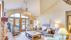 A spacious living room with a fireplace, comfortable seating, and large windows offering a mountain view. - Seasons Lodge at Arrowhead: Beaver Creek Condo! (Edwards)