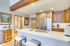 A modern kitchen with wooden cabinets, a stainless steel refrigerator, and a marble countertop. - Seasons Lodge at Arrowhead: Beaver Creek Condo! (Edwards)