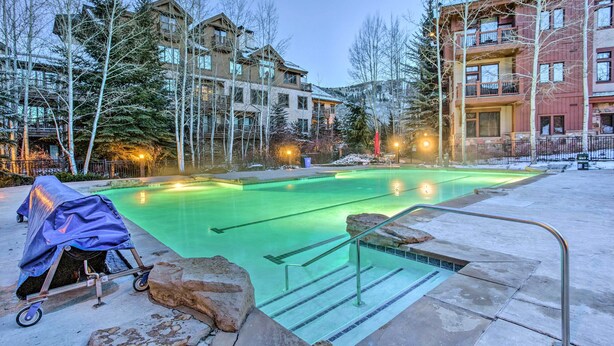 A swimming pool with clear water, surrounded by buildings and trees. - Seasons Lodge at Arrowhead: Beaver Creek Condo! (Edwards)