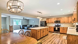 Una cocina moderna con armarios de madera, una isla central y una zona de comedor con mesa y sillas de madera.