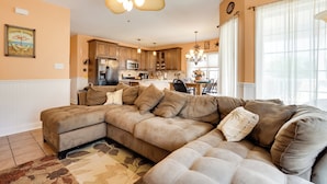 A spacious living room with a large sectional sofa, a dining area with a table and chairs, and a kitchen in the background. - Breezy Wildwood Condo ~ 2 Blocks to Beach! (Wildwood)