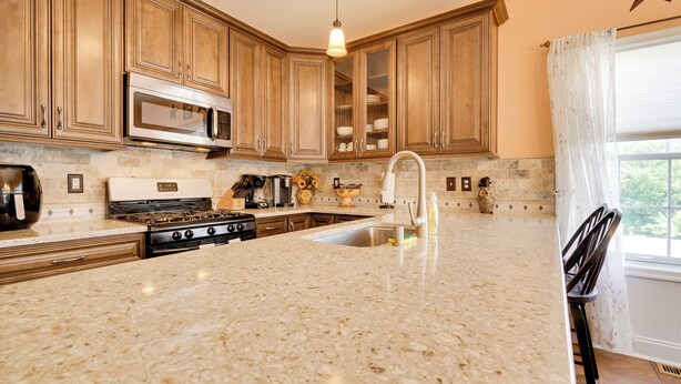 A kitchen with wooden cabinets, a granite countertop, stainless steel appliances, and a window with a star decoration. - Breezy Wildwood Condo ~ 2 Blocks to Beach! (Wildwood)