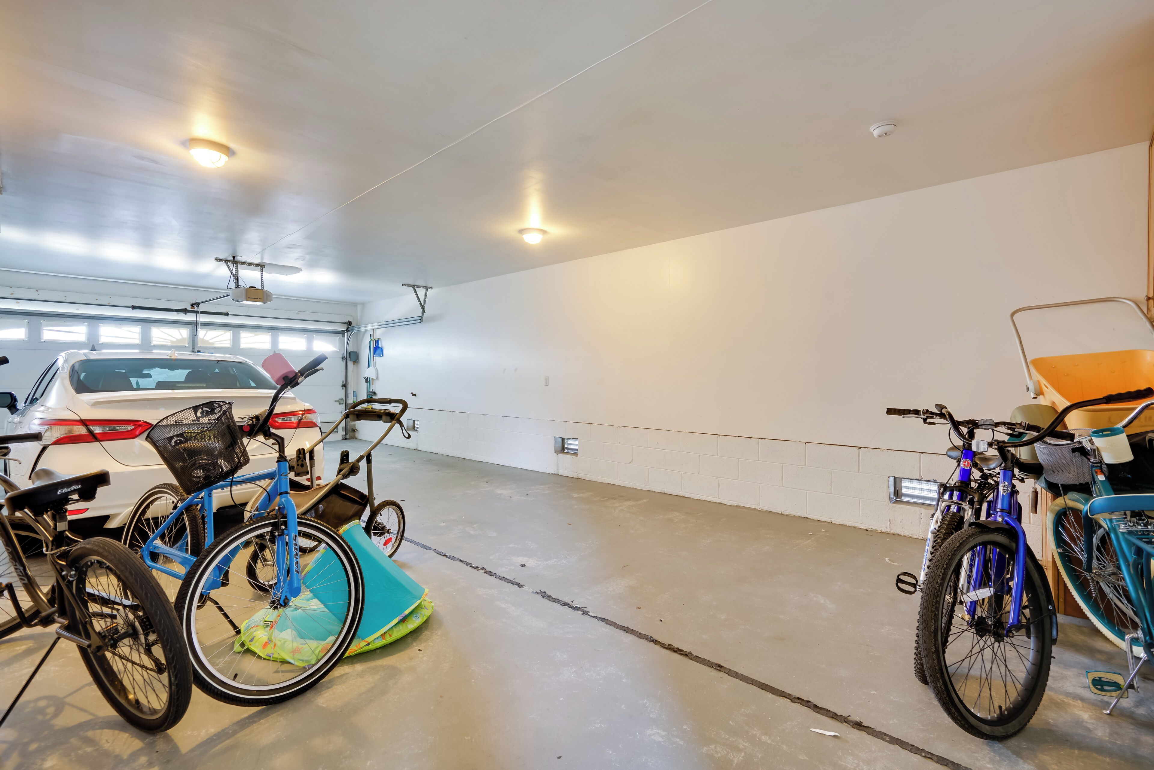 A parking garage with bicycles and a white car.