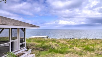 Enjoy a serene ocean view from the covered deck, overlooking the water and adjacent grassy area.
