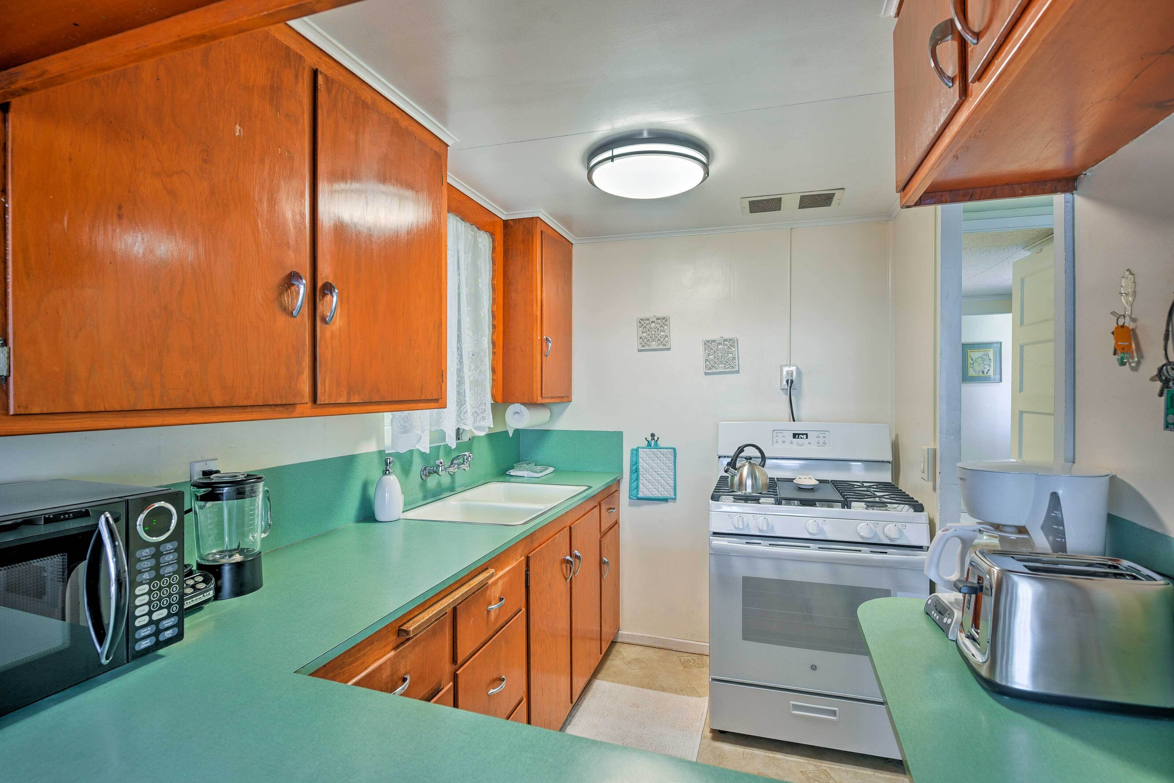A kitchen with wooden cabinets, a microwave, a stove, and a toaster.