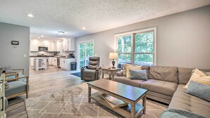 A spacious living area with a sofa, coffee table, and a dining table. There is a kitchen in the background with cabinets and a microwave. - Beulah Family Home ~ 2 Mi to Dtwn + Beach! (Beulah)