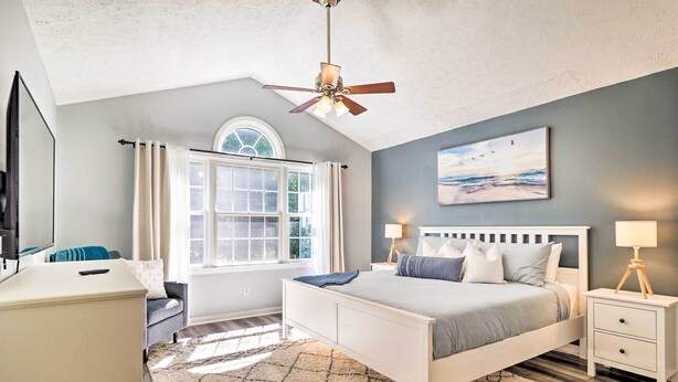 A bedroom with a bed, bedside tables, a ceiling fan, a window with curtains, and a painting on the wall. - Beulah Family Home ~ 2 Mi to Dtwn + Beach! (Beulah)