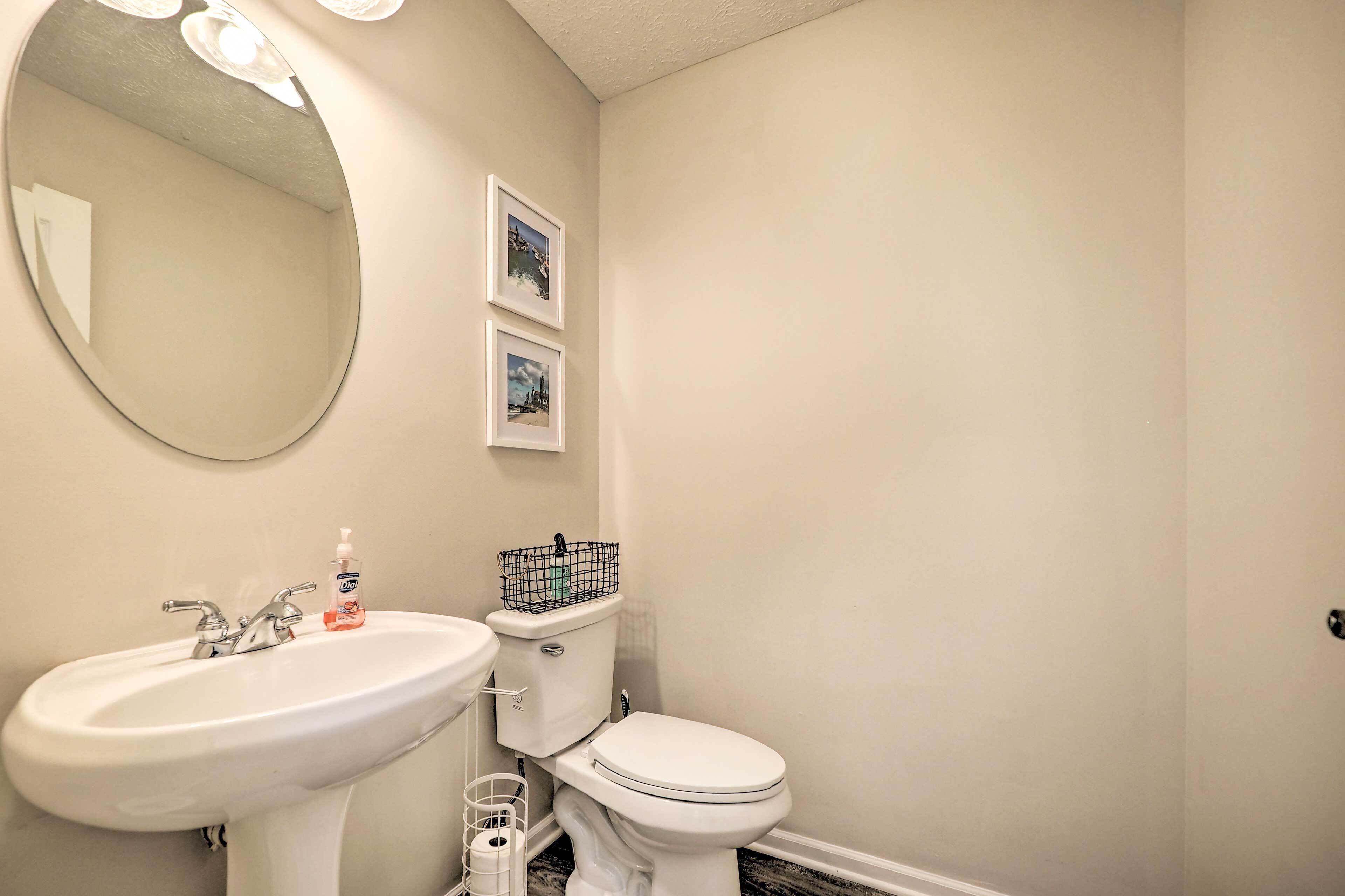 A bathroom with a white sink, toilet, and mirror. There are two framed pictures on the wall.
