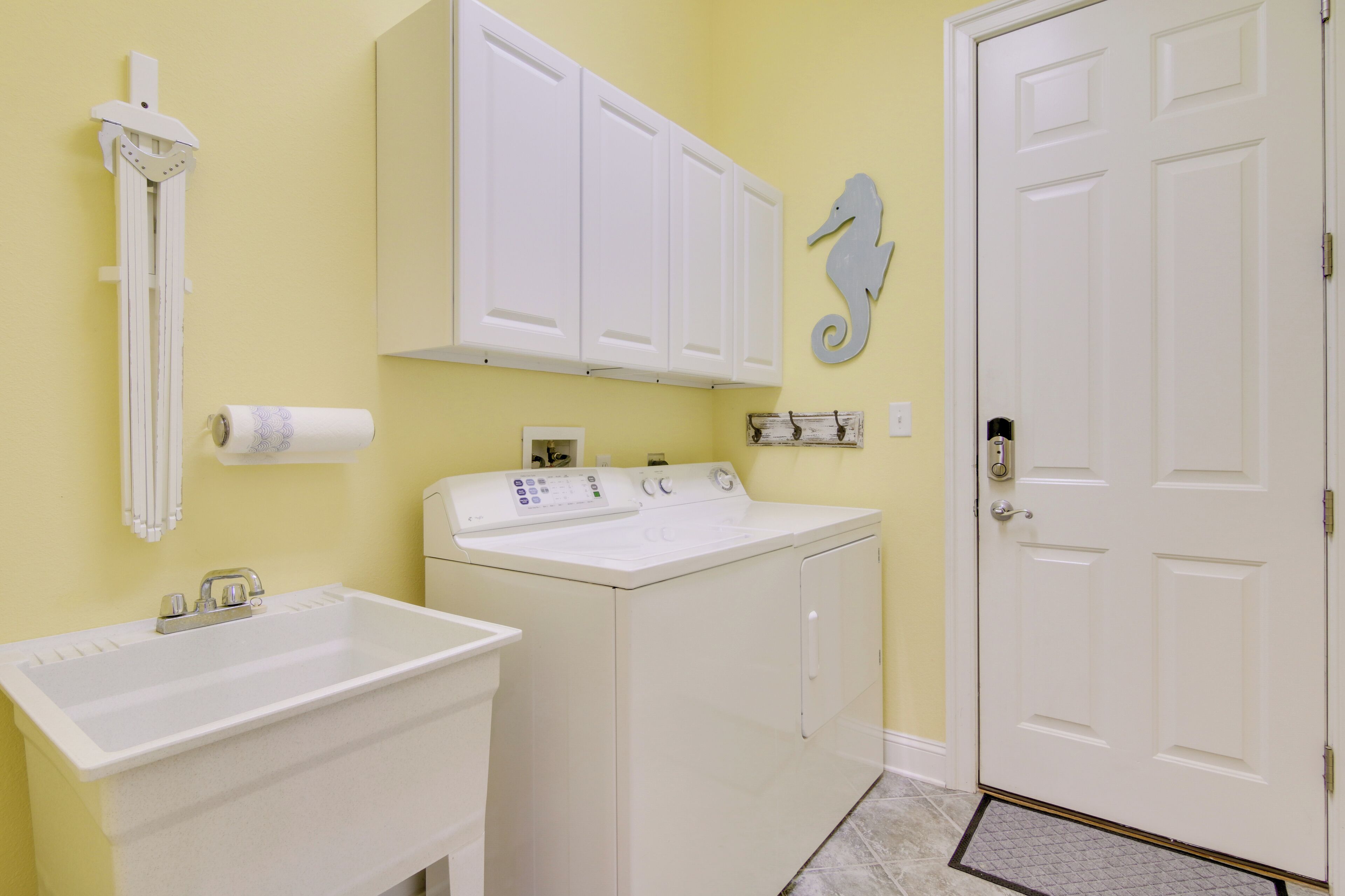 A laundry room with a washing machine, a sink, and a door.