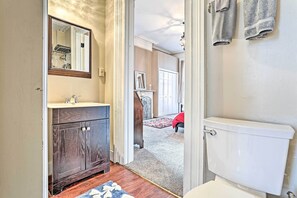 A bathroom with a wooden vanity, a white toilet, and a mirror. - Centrally Located Apt in Victorian Mansion! (Poughkeepsie)