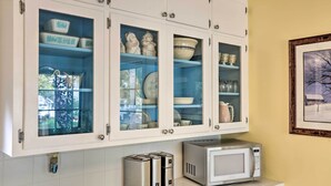 Una cocina con armarios blancos, microondas y tostadora.