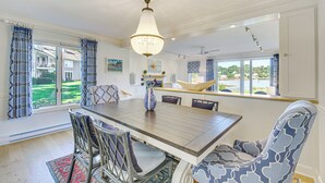 A dining area with a wooden table, wicker chairs, and a chandelier.