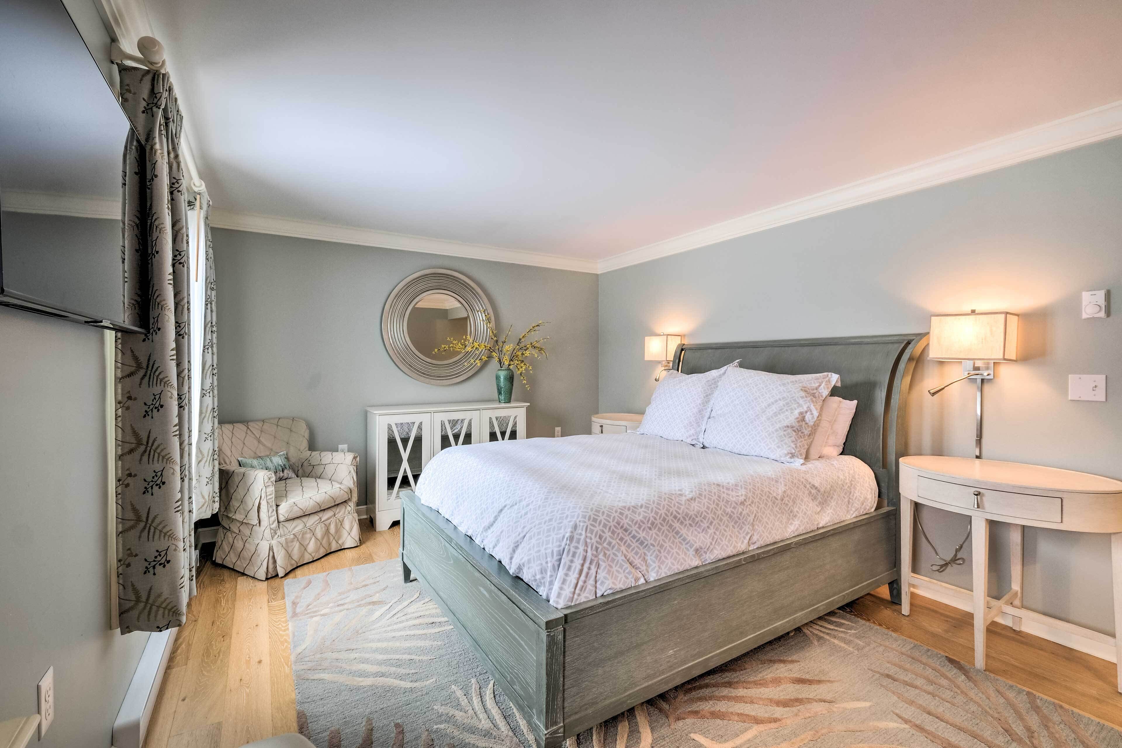 A bedroom with a bed, bedside tables, a chair, a mirror, and a lamp.