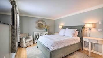 A bedroom with a bed, bedside tables, a chair, a mirror, and a lamp.