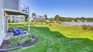 A residential property with a well-maintained lawn, outdoor seating, and a view of a lake.