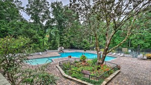 Ein Garten mit Pool, umgeben von einer Pflasterterrasse und üppiger Bepflanzung.