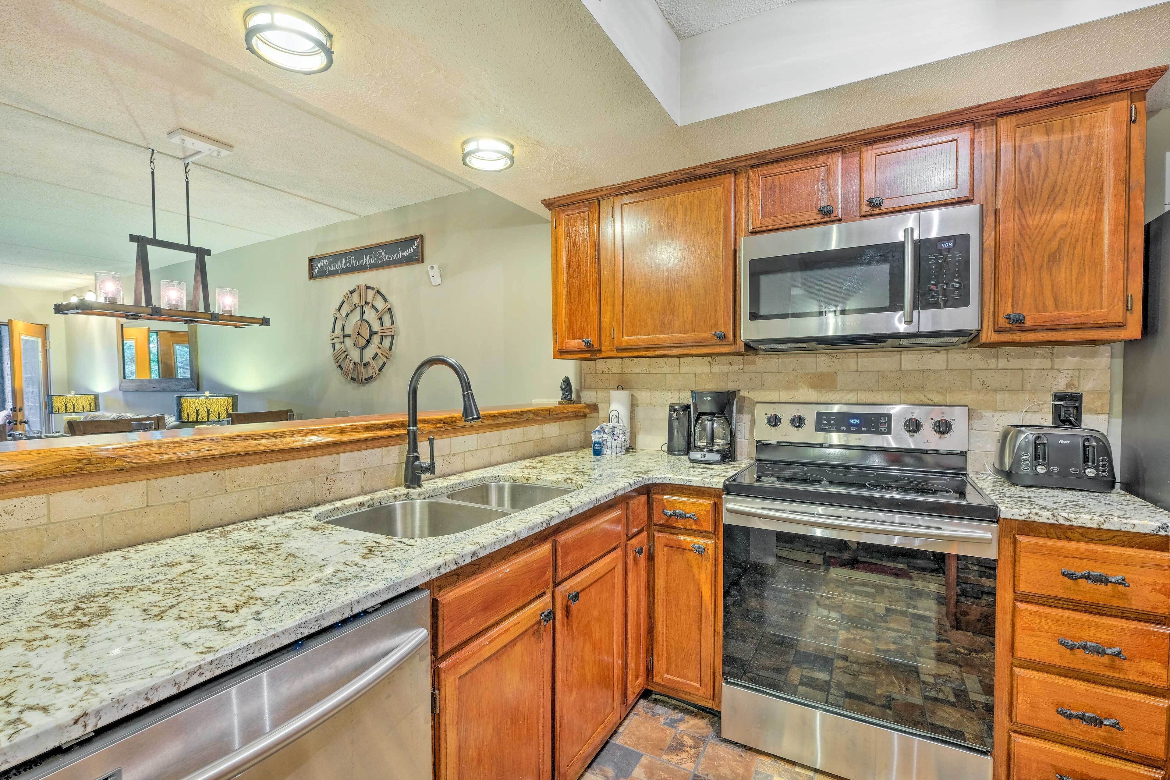 A kitchen with wooden cabinets, stainless steel appliances, a granite countertop, and a brick backsplash.