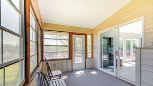 A covered porch with a bench, a door leading to a patio, and large windows. - The View - Waterfront Lake Anna Home w/ Dock! (Bumpass)