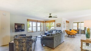 A spacious living room with a sofa, armchair, and a dining table. - The View - Waterfront Lake Anna Home w/ Dock! (Bumpass)