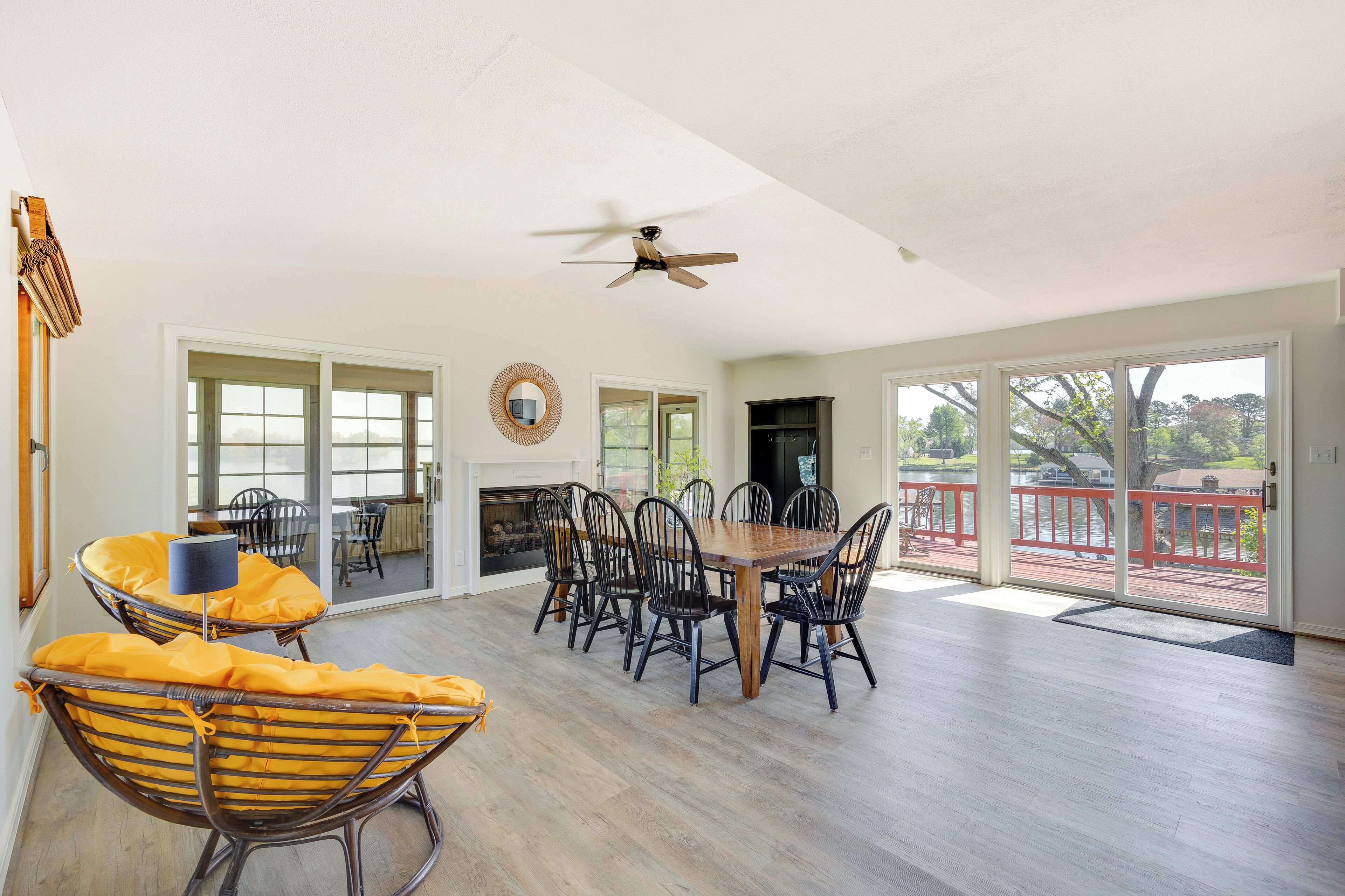 A spacious living room with a wooden dining table, black chairs, and a ceiling fan.