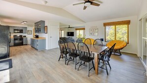 A spacious kitchen with modern appliances, a dining area with wooden tables and chairs, and a ceiling fan. - The View - Waterfront Lake Anna Home w/ Dock! (Bumpass)