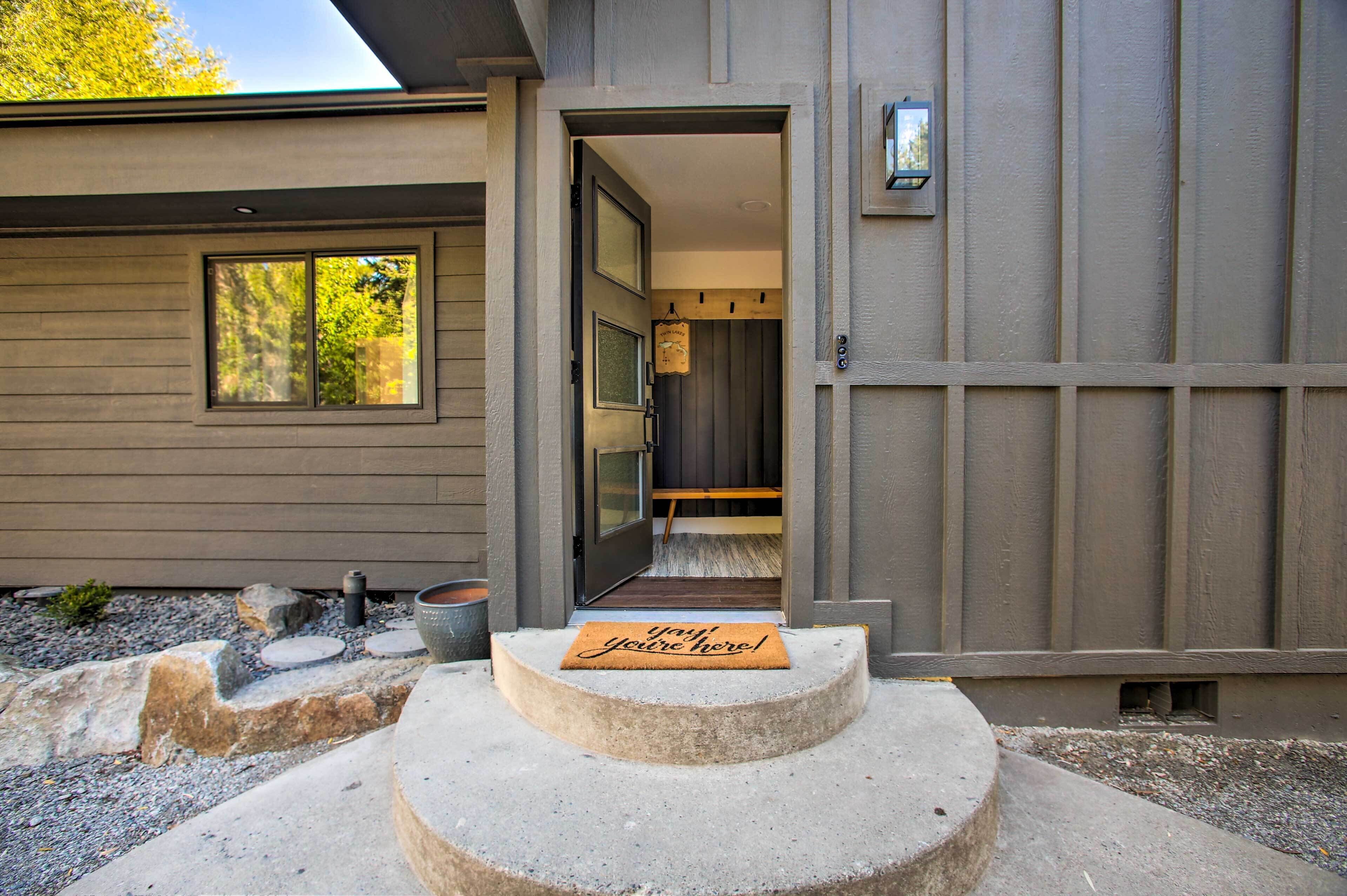 Una entrada de casa moderna con un escalón de concreto, un felpudo y una puerta que da al interior.