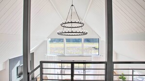 A spacious room with a high ceiling, a large window, and a modern chandelier. - A Contemporary Dream: Lakefront Rathdrum Oasis! (Rathdrum)