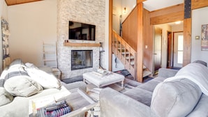 A cozy living room with a stone fireplace, a staircase, and a comfortable seating area. - Charming Townhome - Walk to Greek Peak Mountain! (Cortland)