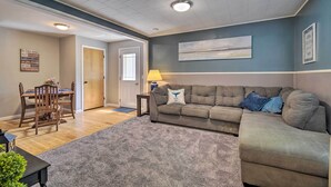 A living room with a grey sofa, a dining table with chairs, a lamp, and a rug. - Peaceful Finger Lakes Apartment With Patio! (Ovid)