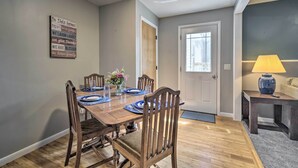A dining room with a wooden table set for six, a vase with flowers, and a sign on the wall. - Peaceful Finger Lakes Apartment With Patio! (Ovid)