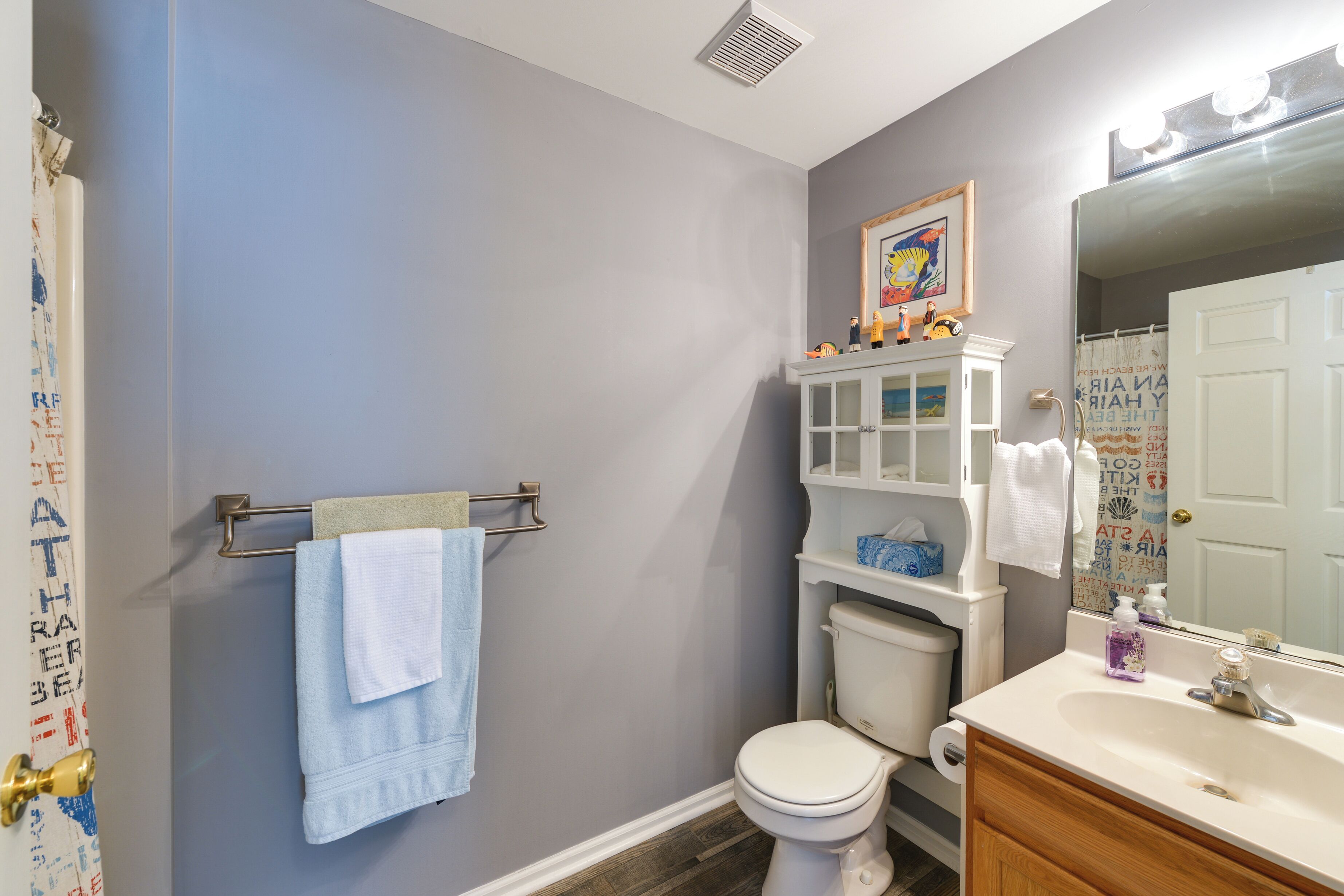 A bathroom with a toilet, sink, and a towel rack with two towels.