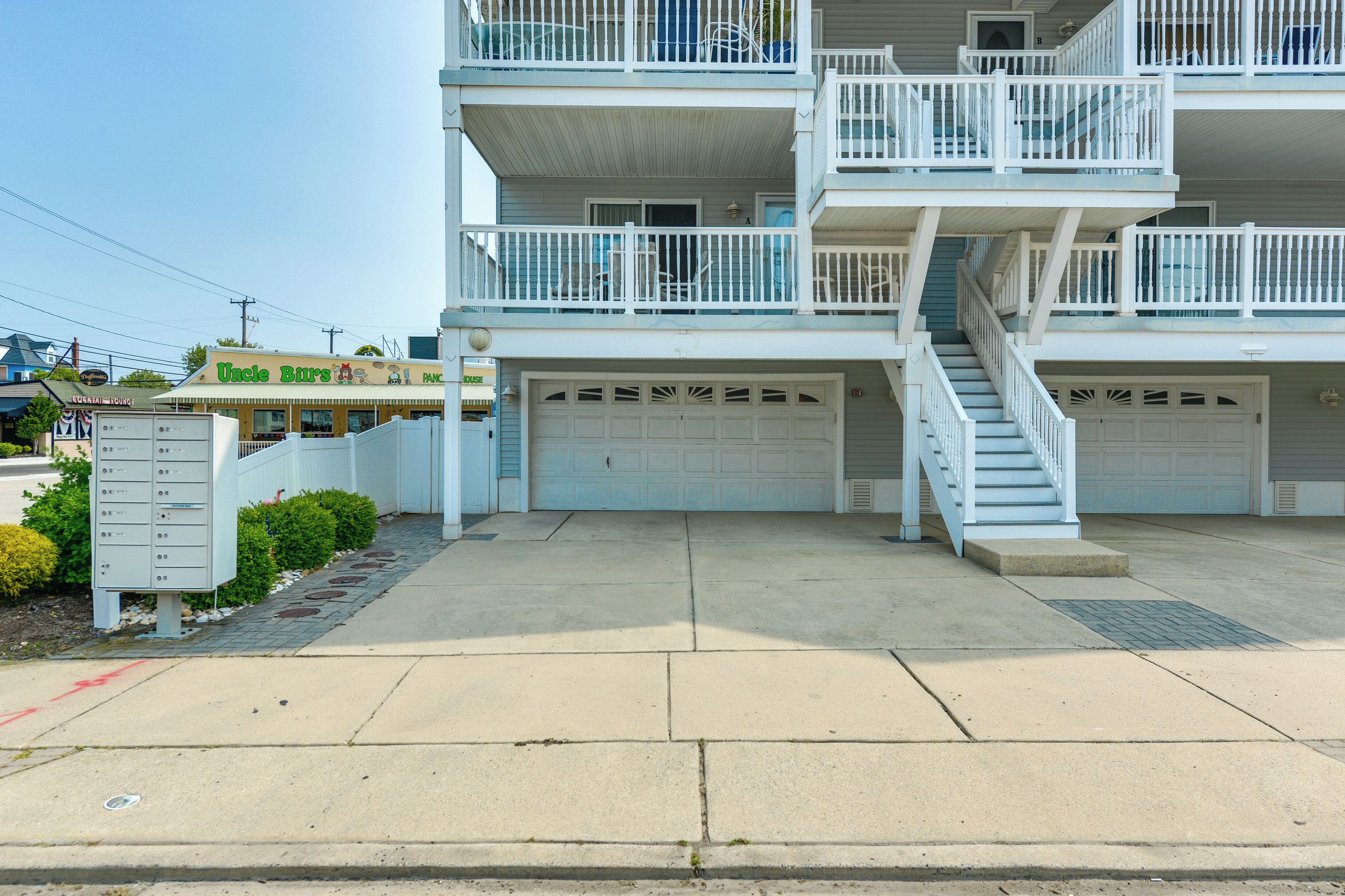 A multi-story residential building with a garage on the ground floor, a balcony on the second floor, and a staircase leading to the upper levels.