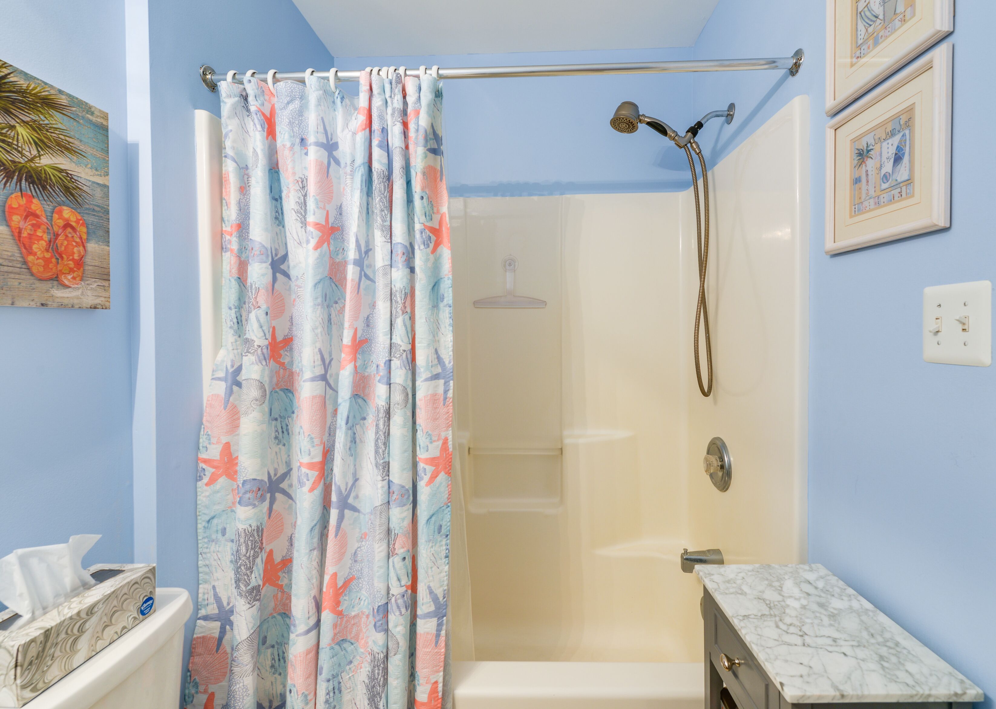 Une salle de bain équipée d’une douche, de toilettes et d’un meuble-lavabo surmonté d’un plan en marbre.