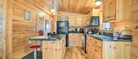 A wooden cabin interior with a kitchen, bar area, and a dining table with chairs.
