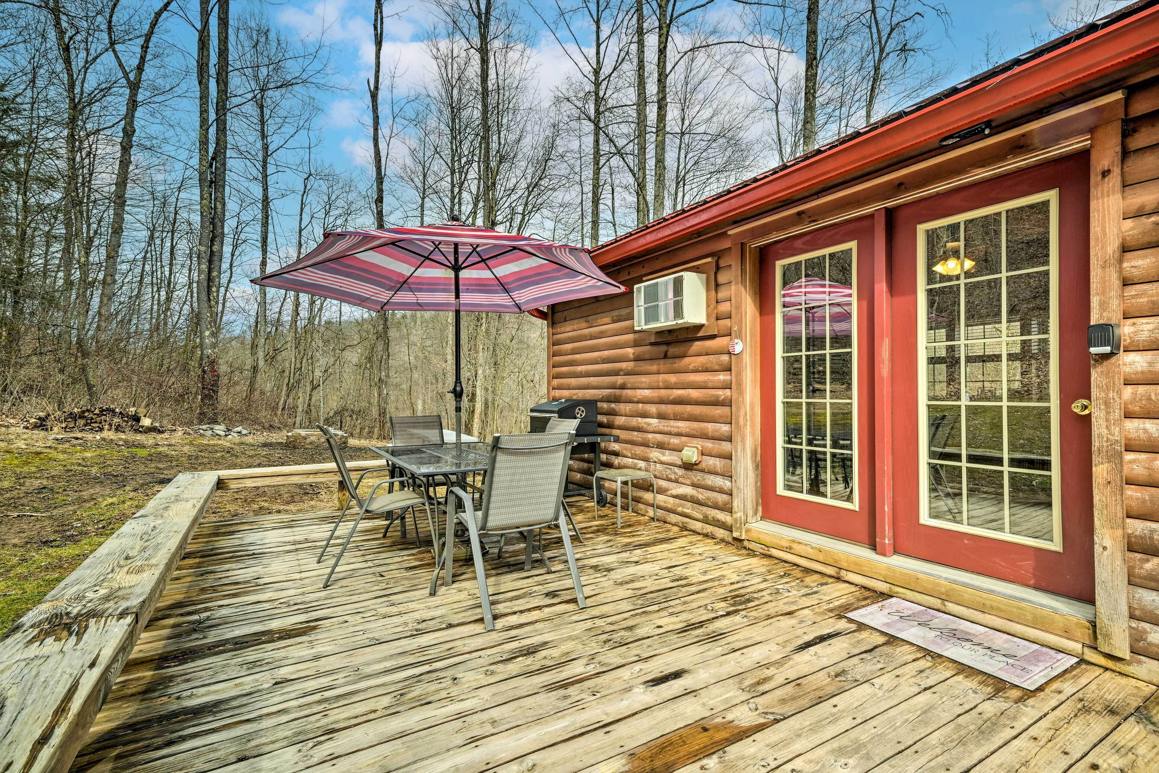 A wooden deck with a table and chairs, a red door, and a window.