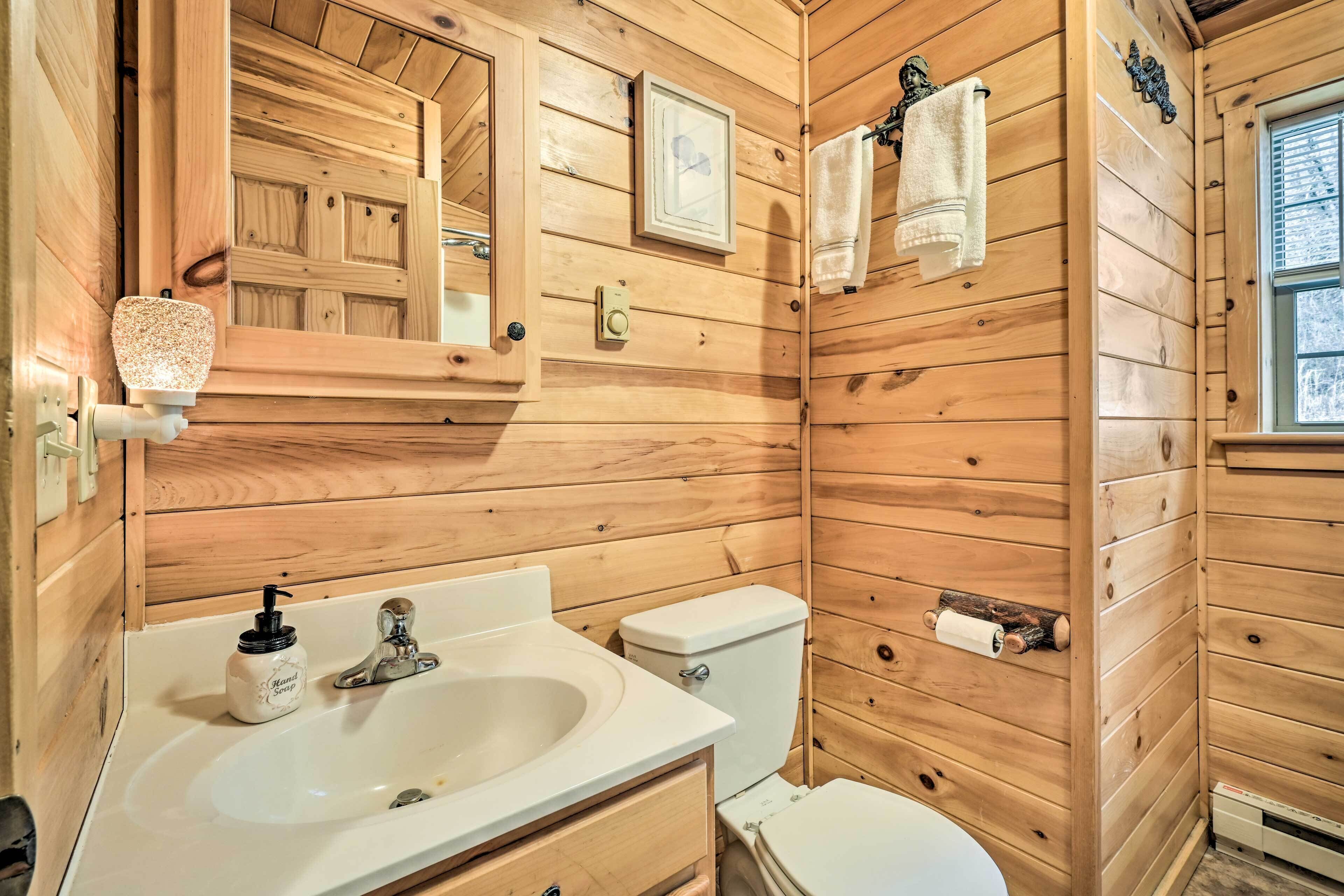 Une salle de bain rustique, aménagée dans une cabane en bois, avec un lavabo, des toilettes et un miroir.