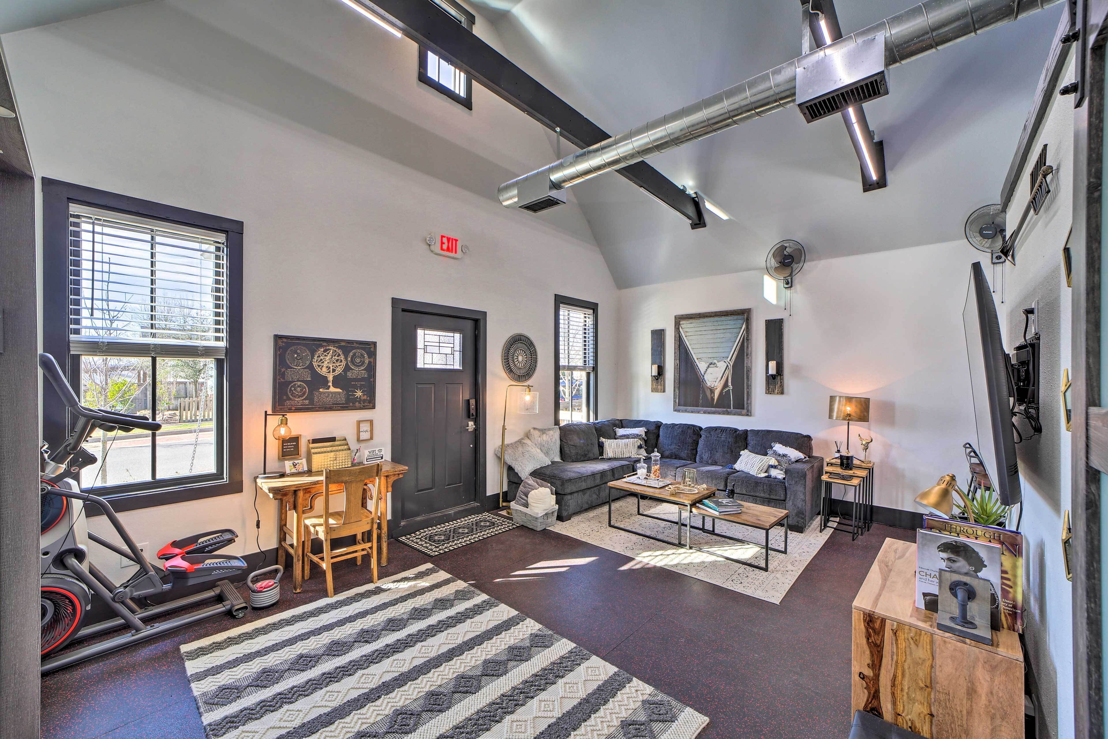 A spacious living area with a treadmill, a sofa, a coffee table, and a fireplace.
