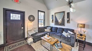 A modern living room with a dark door, a sectional sofa, a coffee table, and a lamp. - Cozy Carlton Landing Home - Near Lake Eufaula (Eufaula)