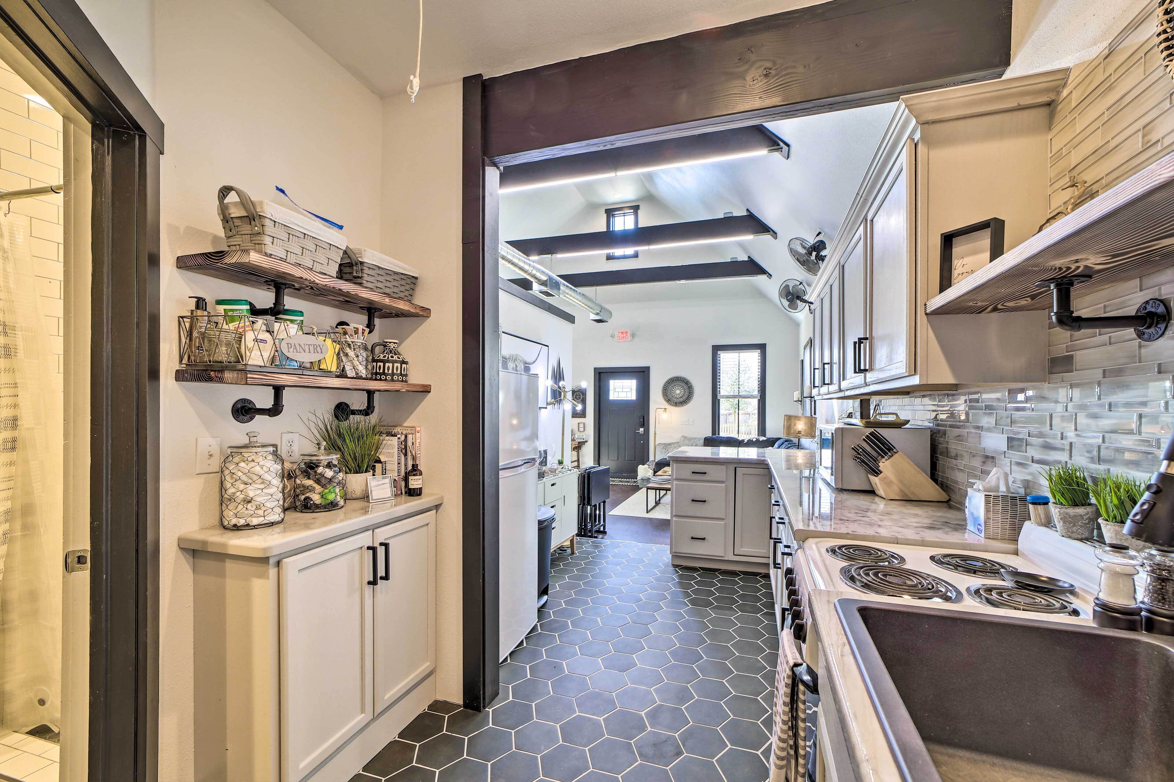 A modern kitchen with a central island, built-in appliances, and a hexagonal tile floor.