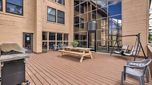 A wooden deck with a picnic table and chairs, a grill, and a swing set. - Cozy Brian Head Condo Near Hiking & Biking! (Brian Head)
