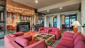A spacious lobby with red upholstered seating, a glass coffee table, and a fireplace. - Cozy Brian Head Condo Near Hiking & Biking! (Brian Head)