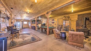 A spacious lodge with a wooden interior, a pool table, a fireplace, and a bar area.