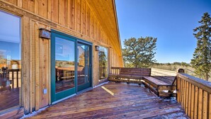 A wooden deck with a bench, a sliding glass door, and a view of the outdoors.