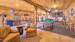 A cozy, rustic room with a pool table, wooden furniture, and a bar area.