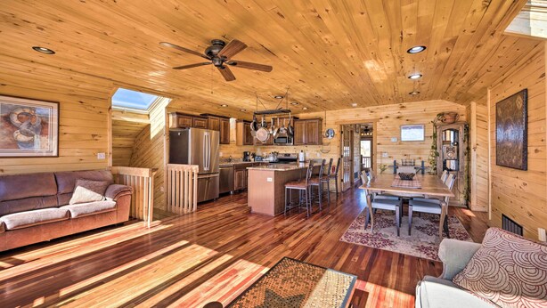 A spacious log cabin interior with a dining area, kitchen, and seating.