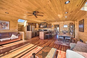 A spacious log cabin interior with a dining area, kitchen, and seating. - Cozy Cripple Creek Cabin w/ Mountain Views! (Victor)